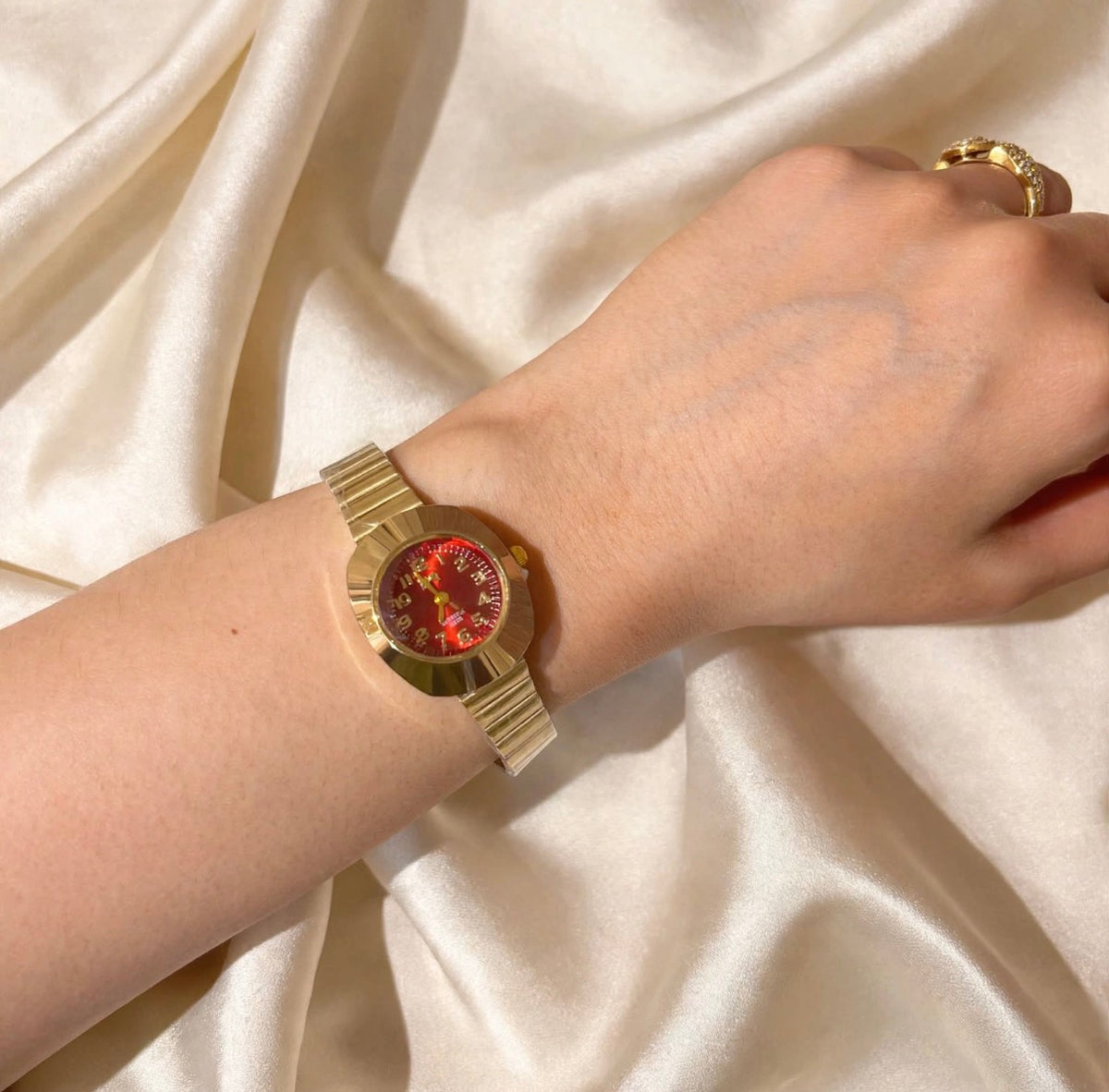 Gentle women’s gold-tone watch with red dial worn on wrist