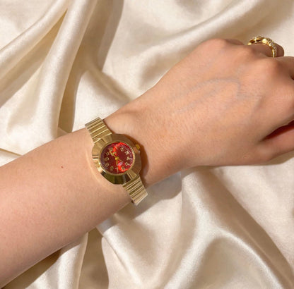 Gentle women’s gold-tone watch with red dial worn on wrist